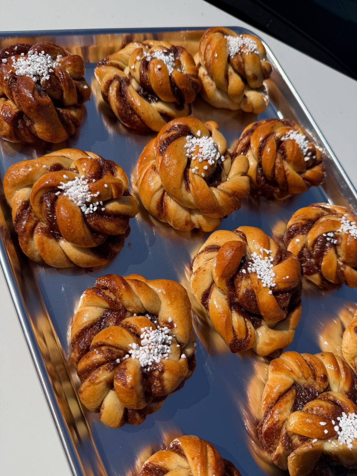 Twisted cinnamon brioche rolls on a baking tray