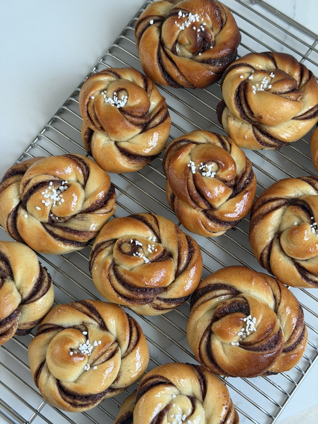 Freshly baked twisted cinnamon buns on a cooling rack